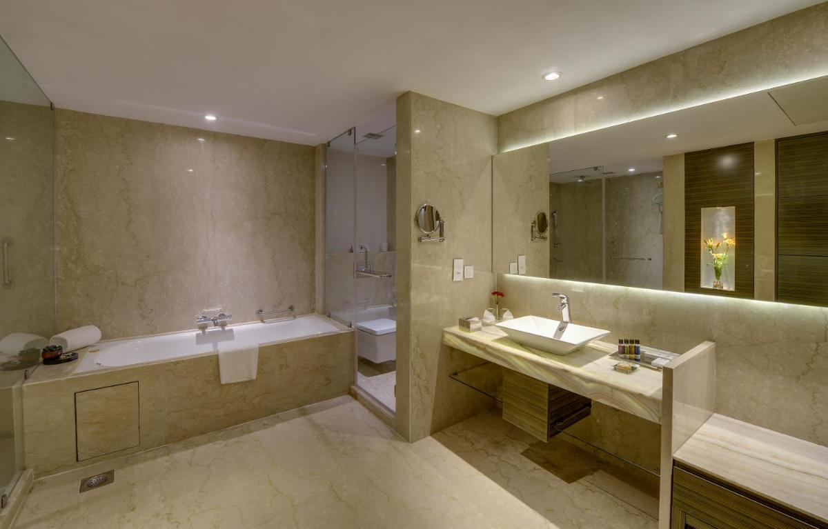 a large bathroom with a tub and a sink and a tubermott at Pride Plaza Hotel, Kolkata in Kolkata