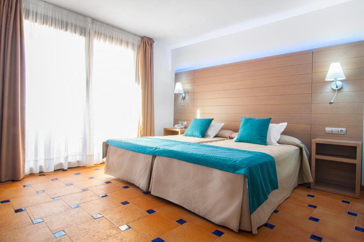 Una habitación de hotel con una cama grande con sábanas azules. en Hotel Sierra de Cazorla & SPA 3*, en Cazorla