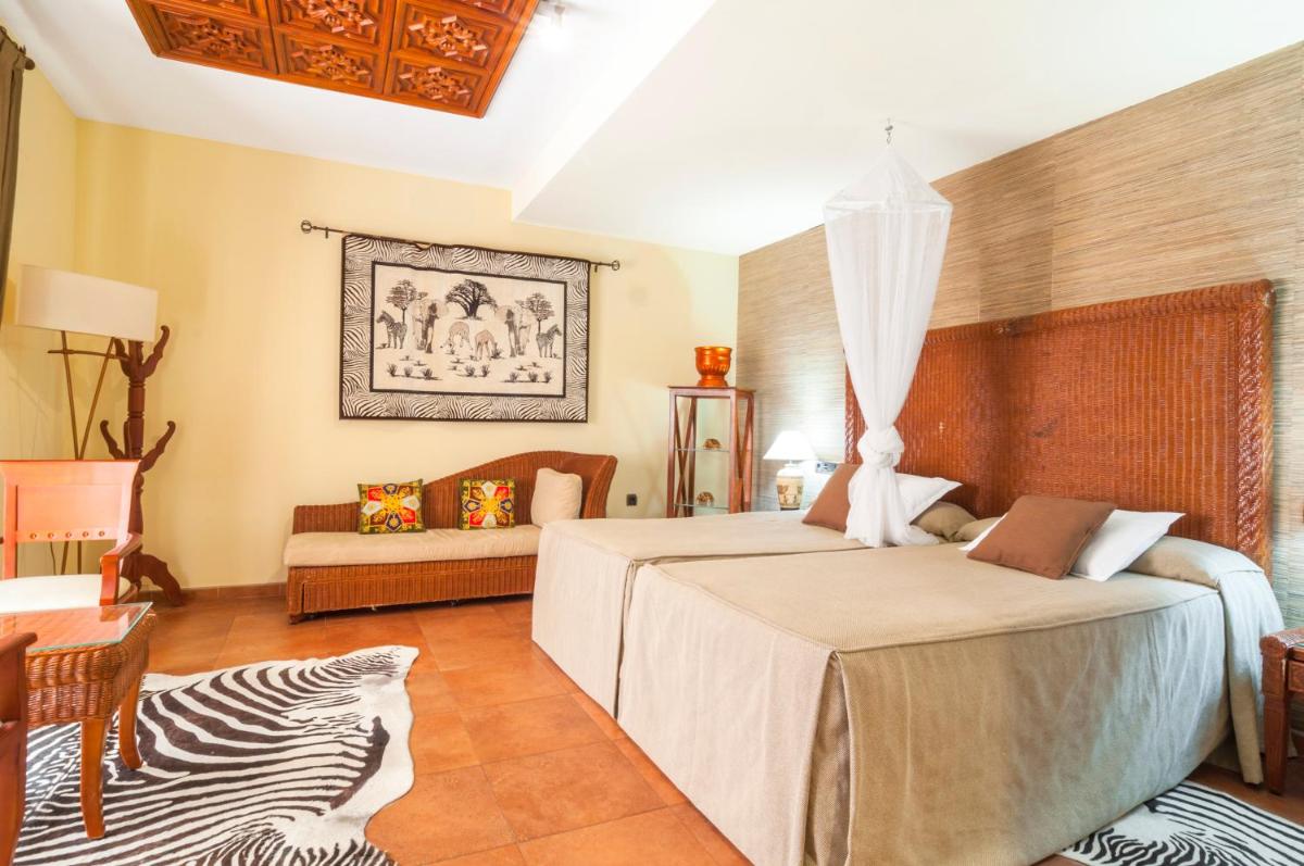un dormitorio con dos camas y un sofá en Hotel & Spa Sierra de Cazorla 4*, en Cazorla
