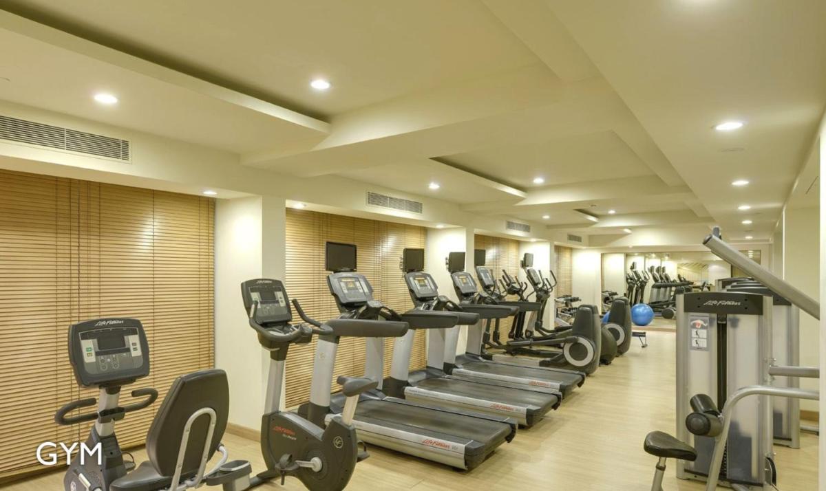 a gym with a row of treadmills and machines at Radisson Blu Bengaluru Outer Ring Road in Bengaluru
