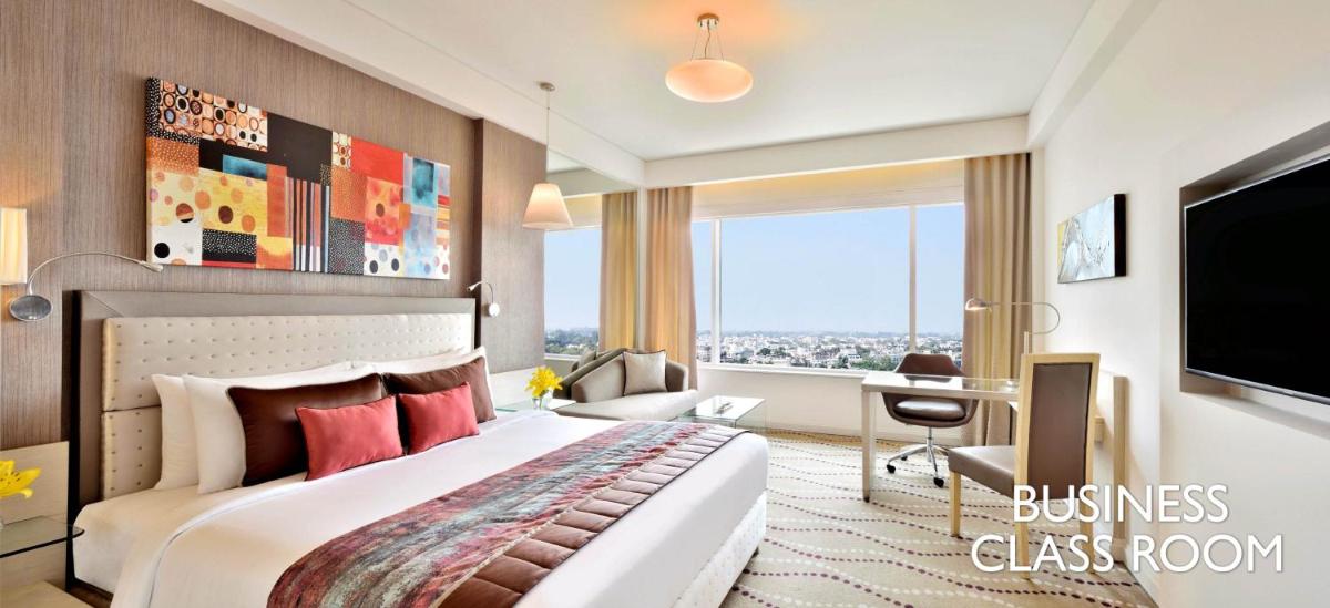 a bedroom with a bed and a desk and a television at Radisson Blu Bengaluru Outer Ring Road in Bengaluru