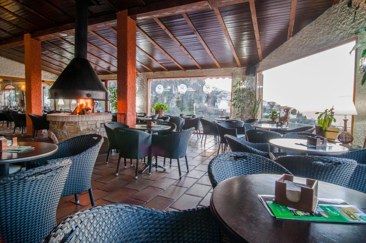 Un restaurante con mesas y sillas y chimenea. en Hotel Sierra de Cazorla & SPA 3*, en Cazorla