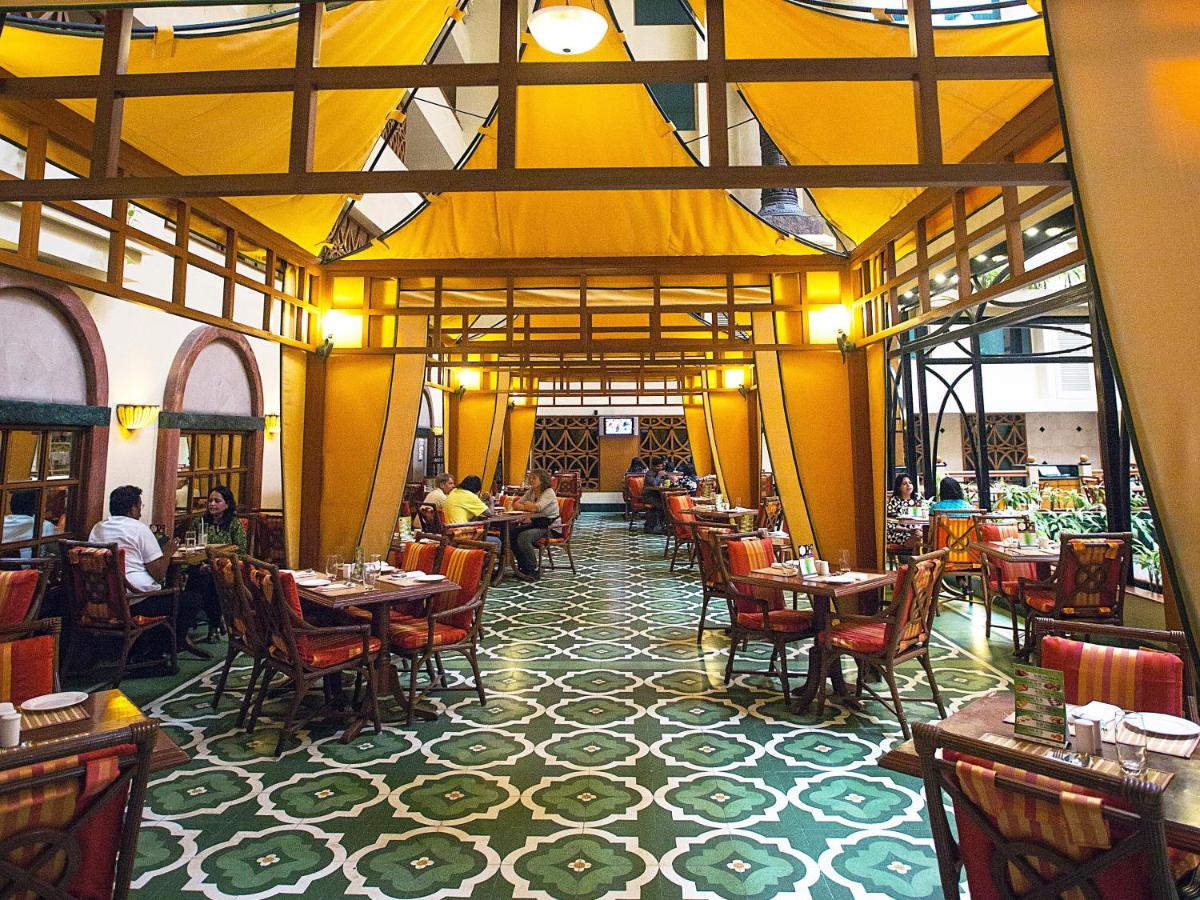 a restaurant with tables and chairs and people sitting at tables at The Orchid Hotel Mumbai Vile Parle in Mumbai a restaurant with tables and chairs and people sitting at tables at The Orchid Hotel Mumbai Vile Parle in Mumbai