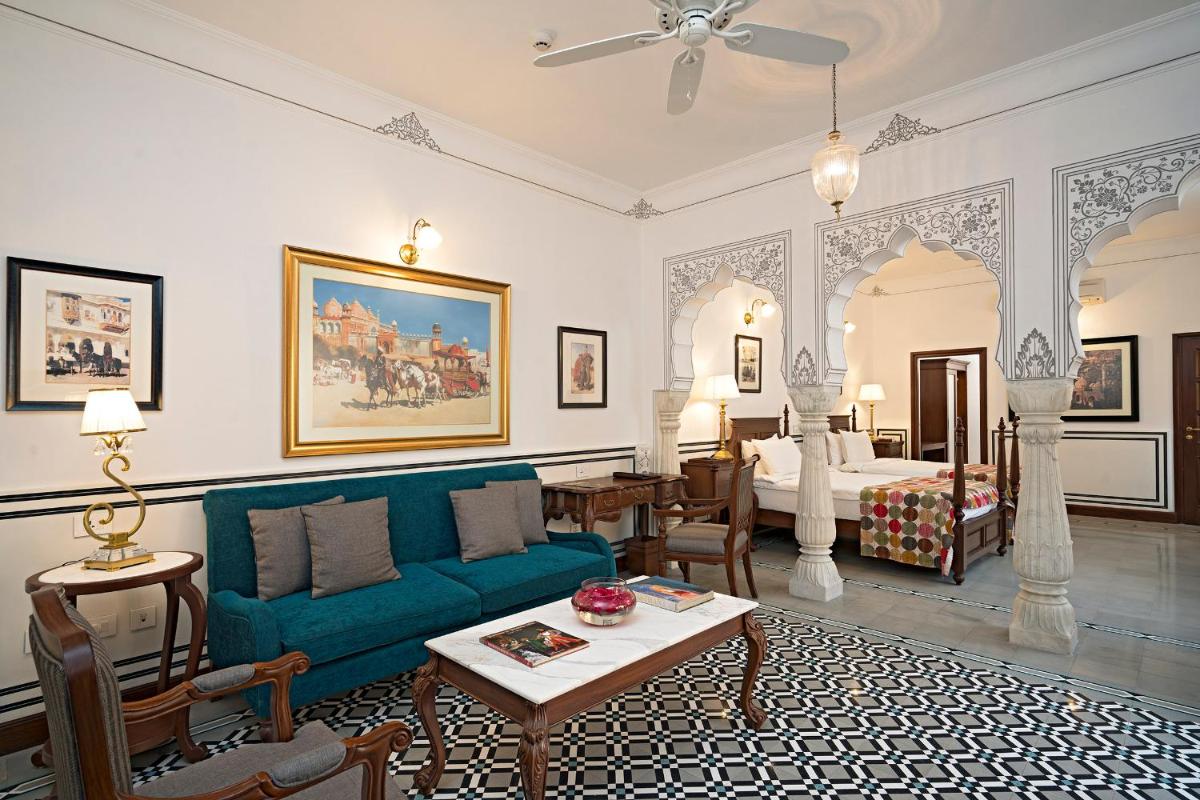 a living room with a blue couch and a bedroom at Samode Haveli in Jaipur