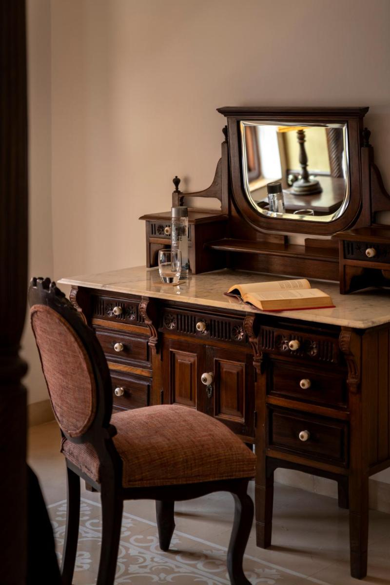 a wooden desk with a mirror and a chair at The Postcard Cuelim, Goa in Cansaulim
