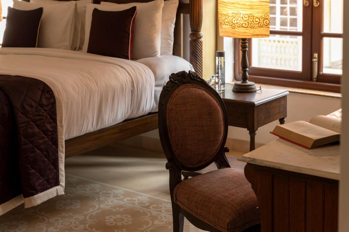 a bedroom with a bed and a desk and a chair at The Postcard Cuelim, Goa in Cansaulim