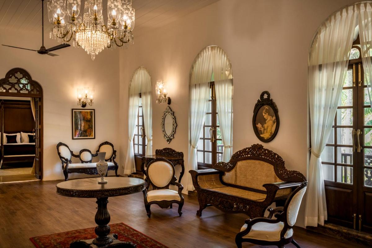 a living room with chairs and a table and a chandelier at The Postcard Cuelim, Goa in Cansaulim