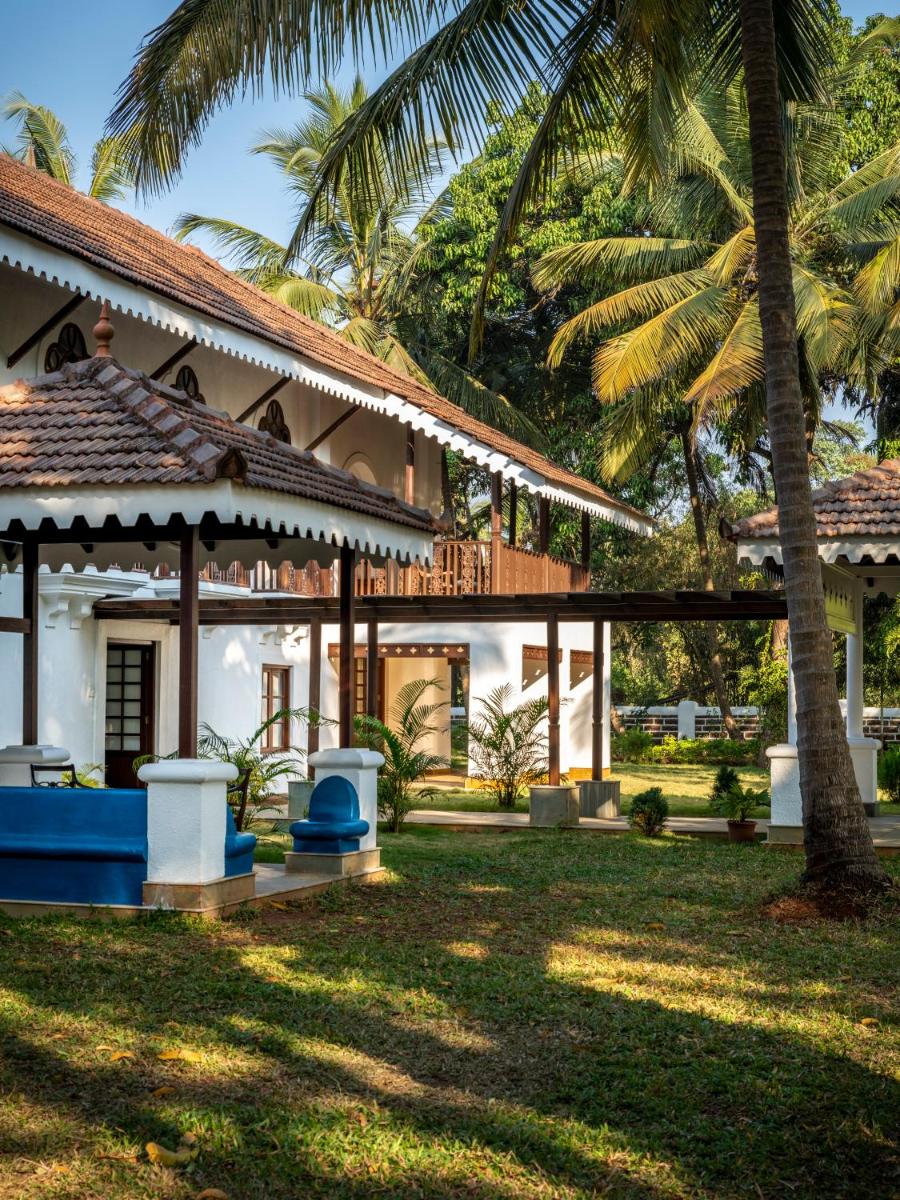 a house with a palm tree in front of it at The Postcard Cuelim, Goa in Cansaulim