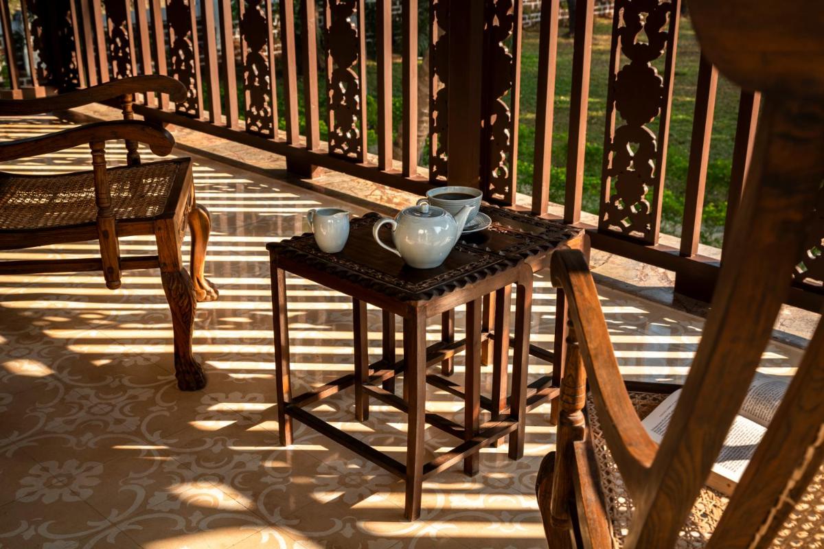a small table on a porch with two mugs on it at The Postcard Cuelim, Goa in Cansaulim