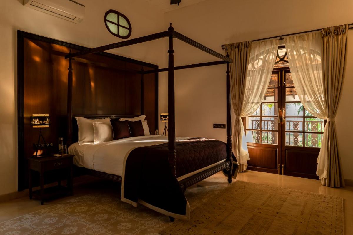 a bedroom with a canopy bed and a window at The Postcard Cuelim, Goa in Cansaulim