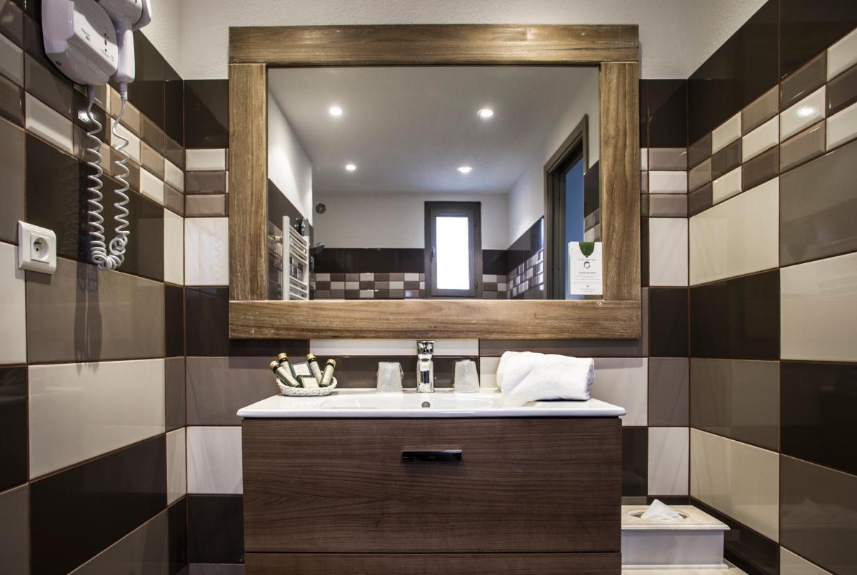 une salle de bains avec un lavabo et un miroir dans l'établissement Le Roc E Fiori Hotel - Teritoria, à Porto-Vecchio