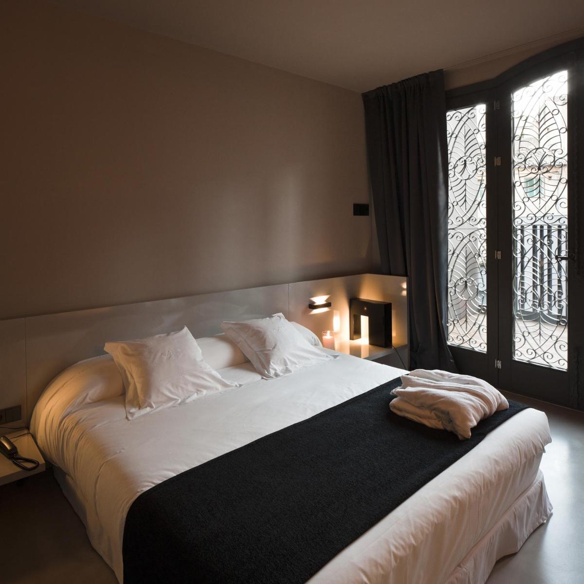 Un dormitorio con una gran cama blanca con ventana. en Caro Hotel, en Valencia