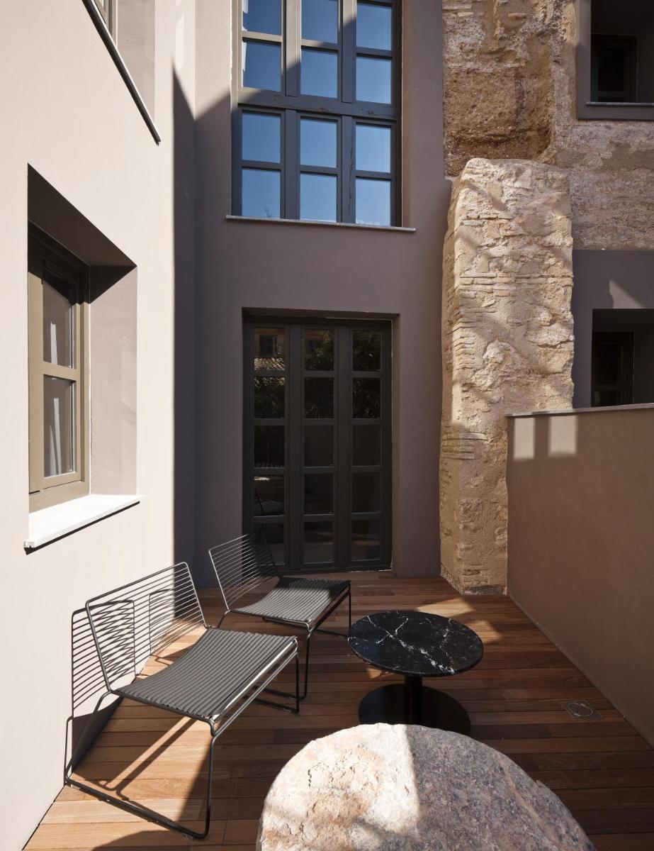 un patio con 2 bancos y una mesa en Caro Hotel, en Valencia