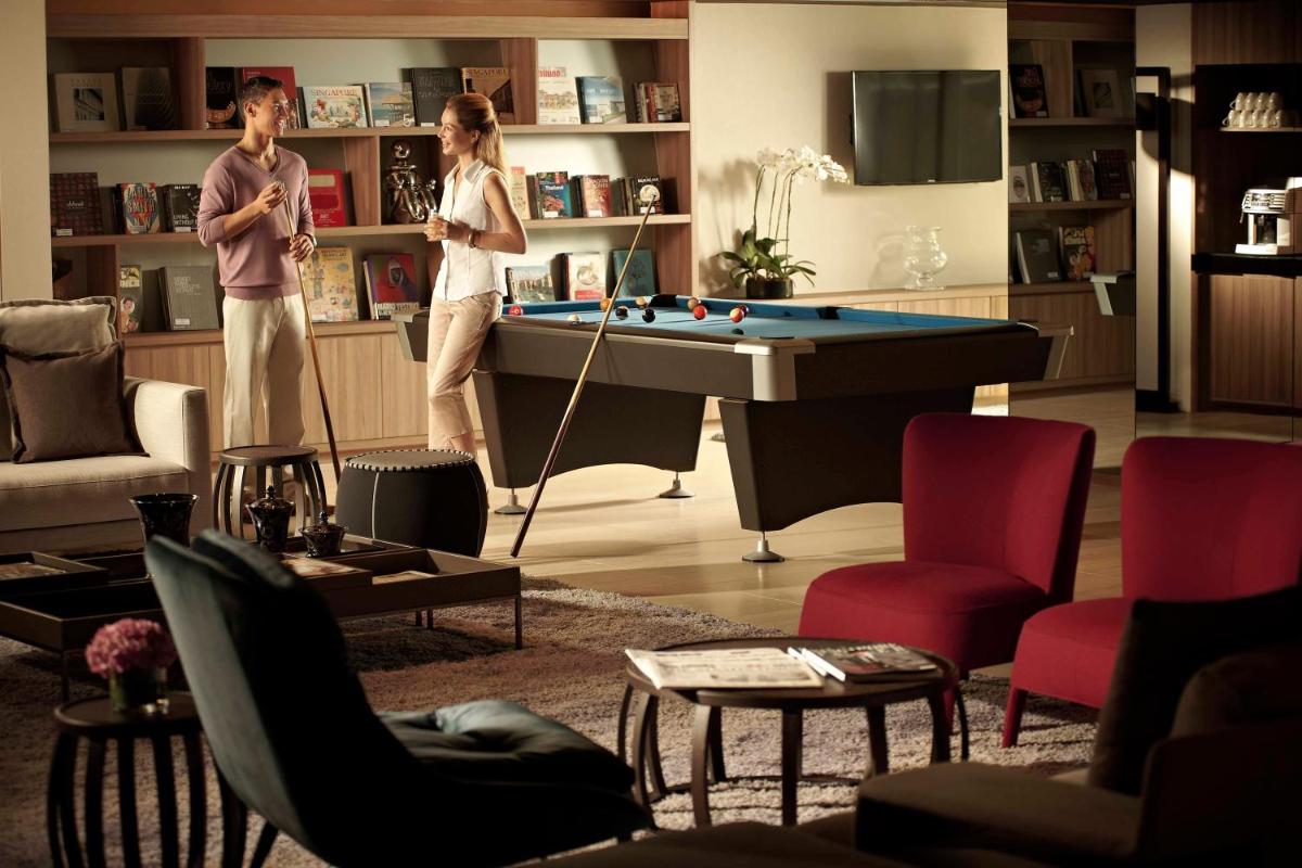 two women standing in a living room with a pool table at Pan Pacific Serviced Suites Beach Road, Singapore in Singapore two women standing in a living room with a pool table at Pan Pacific Serviced Suites Beach Road, Singapore in Singapore