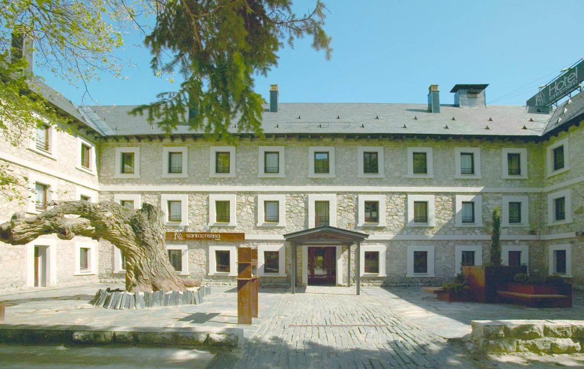 Un gran edificio blanco con un árbol delante. en Hotel Santa Cristina Petit Spa, en Canfranc-Estación