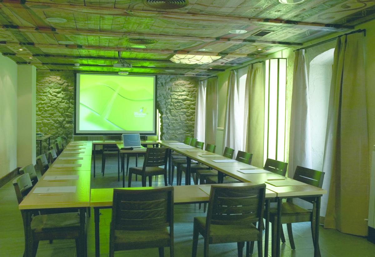 Una sala de conferencias con mesas, sillas y una pantalla. en Hotel Santa Cristina Petit Spa, en Canfranc-Estación 41 fotos más