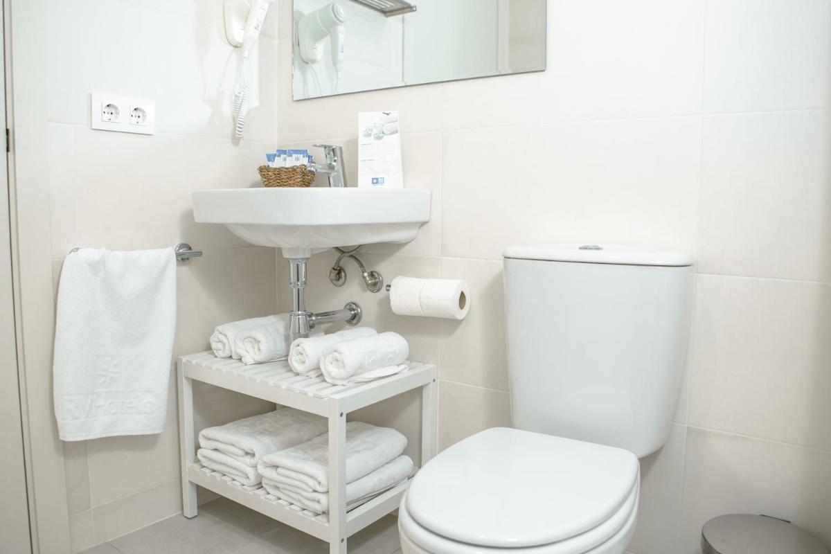 Un baño con inodoro, lavabo y toallas. en Hotel Snö Condes del Pallars, en Rialp