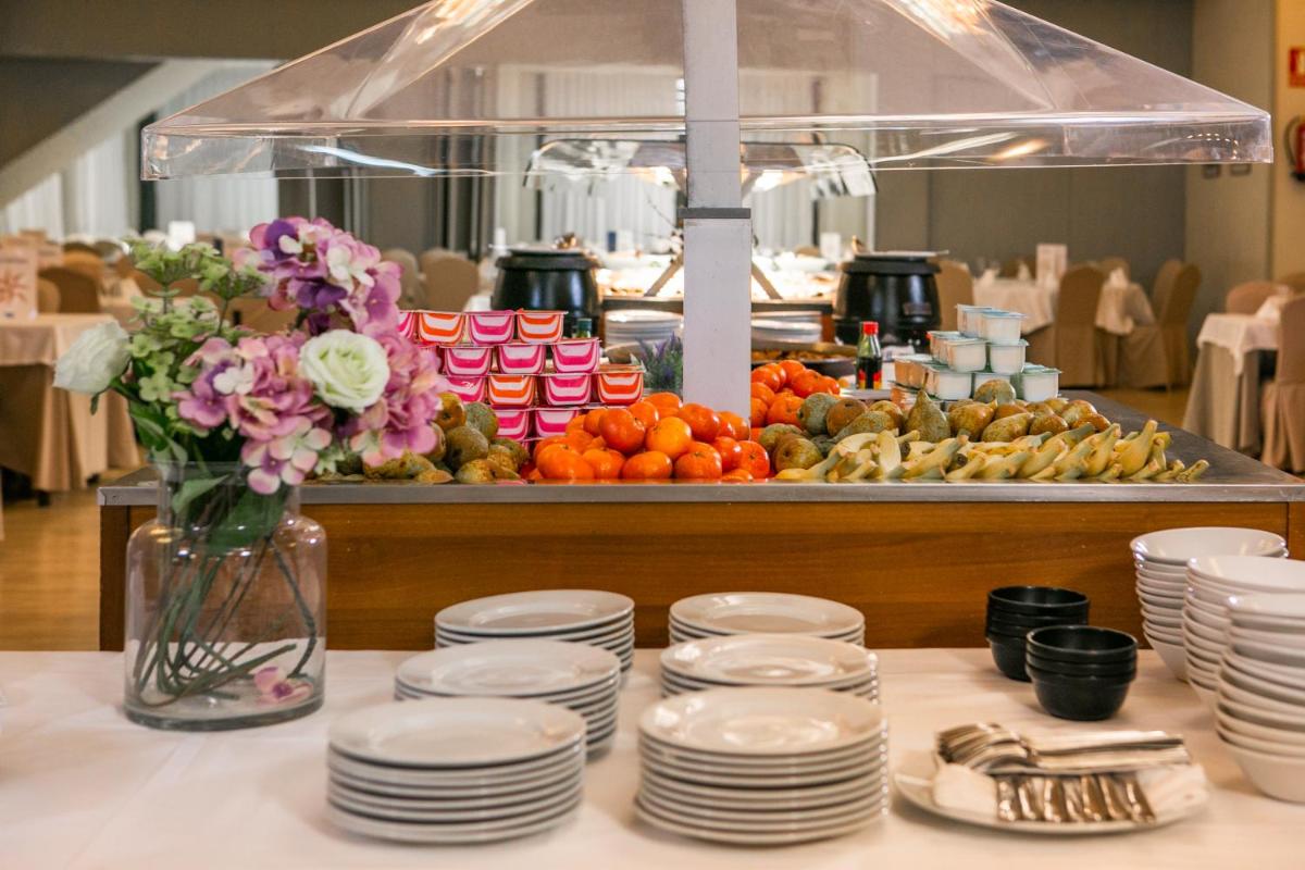 un buffet con platos blancos y flores en una mesa en Hotel Snö Condes del Pallars, en Rialp