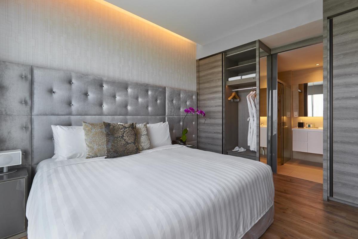 a bedroom with a large bed with a large headboard at Pan Pacific Serviced Suites Beach Road, Singapore in Singapore