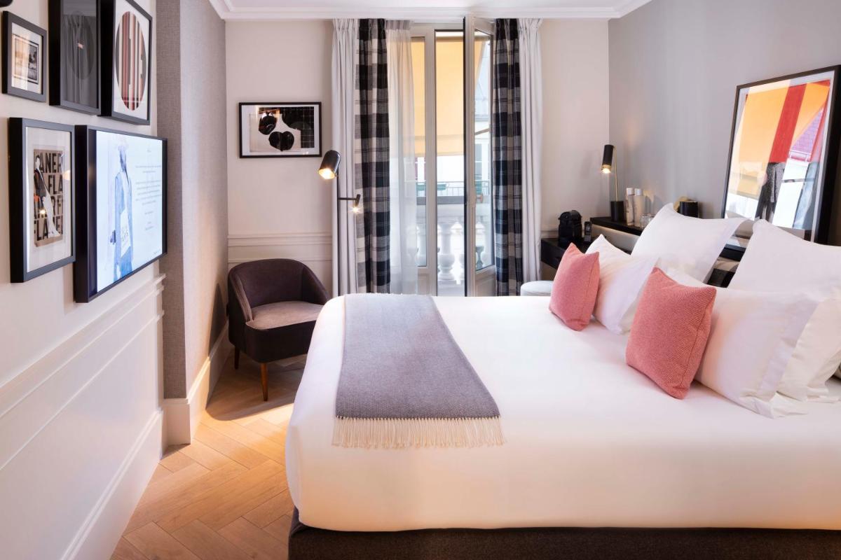 une chambre avec un grand lit blanc et des oreillers roses dans l'établissement Maison ELLE Paris, à Paris