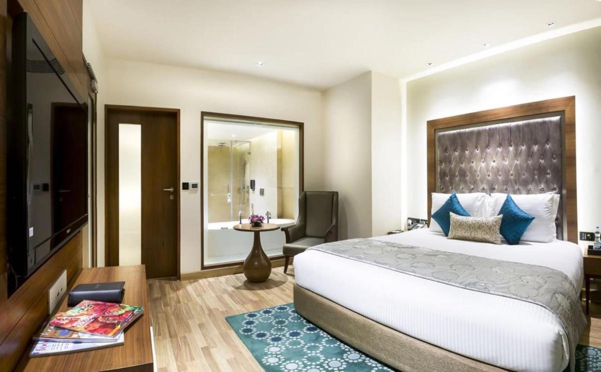 a bedroom with a large bed and a bathroom at Grand Chennai by GRT Hotels in Chennai
