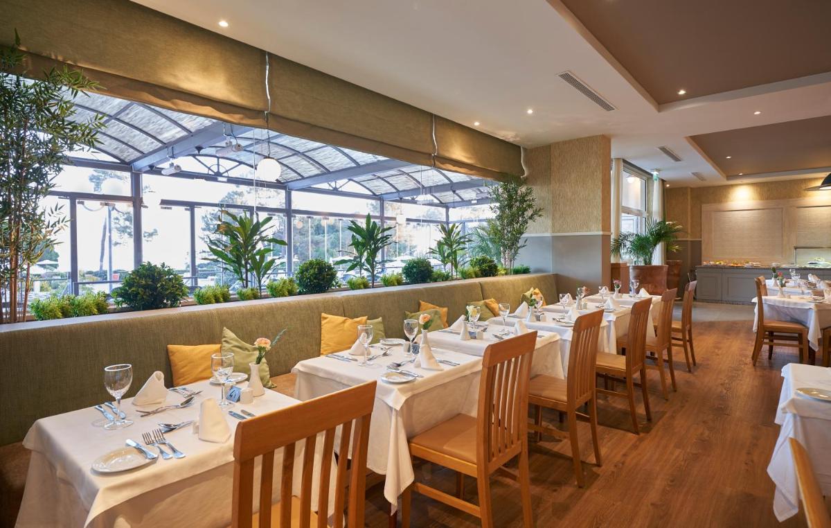 um restaurante com mesas, cadeiras e janelas brancas em PortoBay Falesia em Albufeira