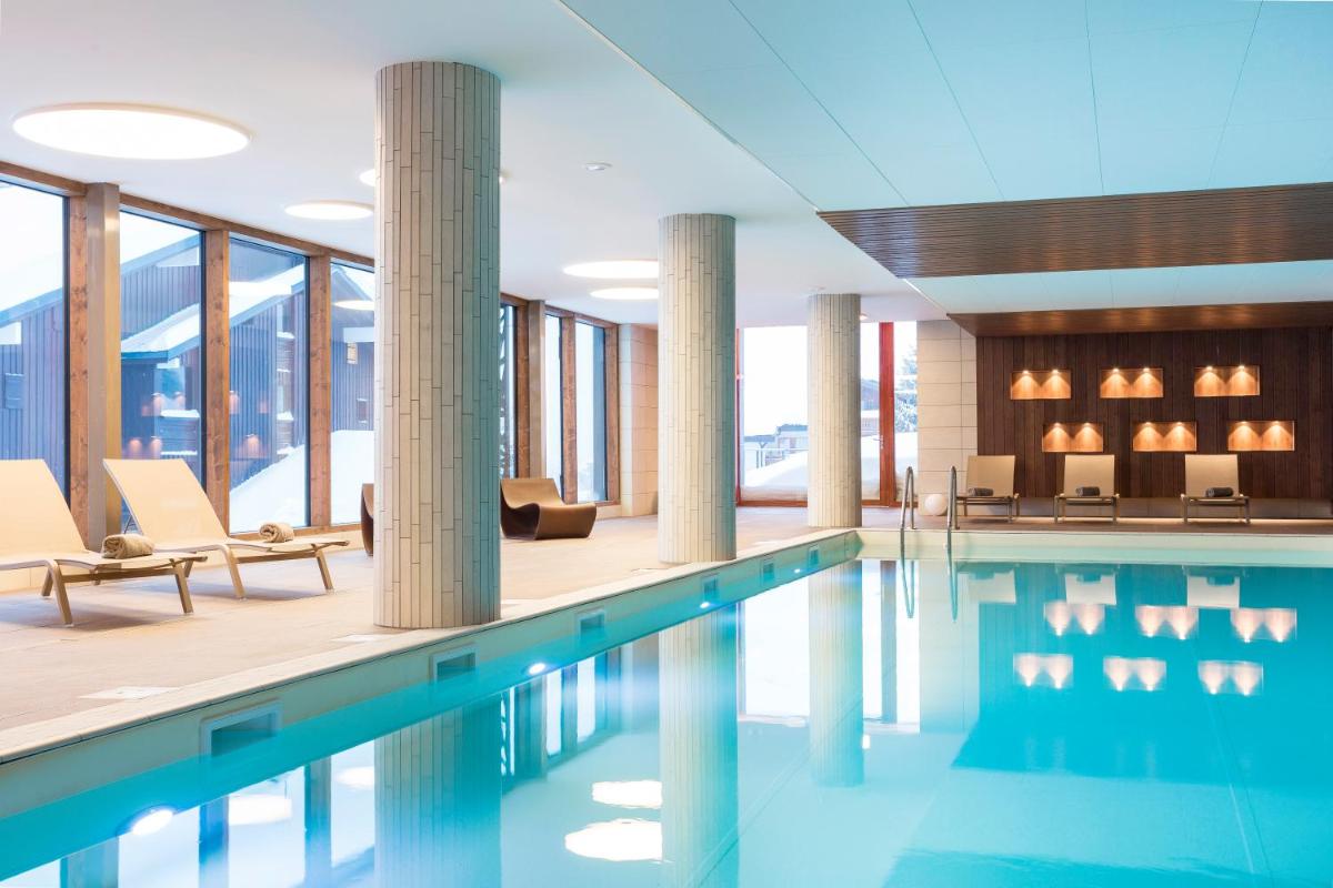 une piscine avec des colonnes et des chaises dans un bâtiment dans l'établissement Résidence Club MMV Les Chalets des Cimes, aux Saisies