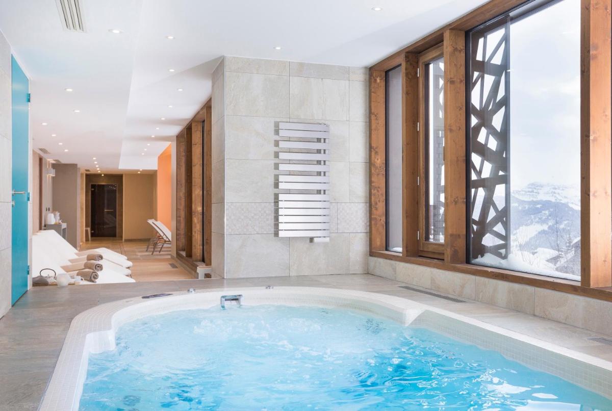 une baignoire jacuzzi dans une chambre avec fenêtres dans l'établissement Résidence Club MMV Les Chalets des Cimes, aux Saisies