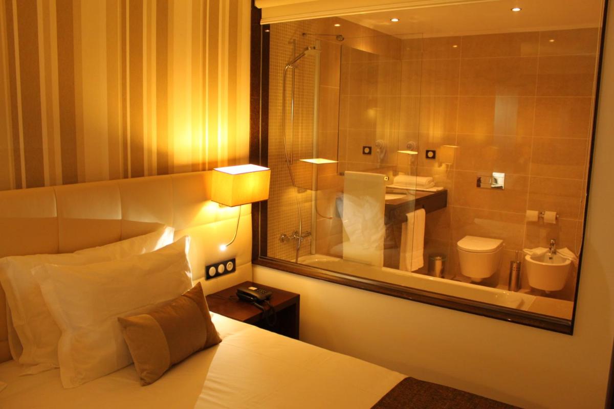 um quarto de hotel com uma cama e um banheiro em Hotel O Gato & Spa em Odivelas