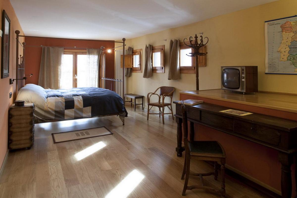Un dormitorio con una cama y un escritorio con televisión. en Posada Real La Vieja Chimenea-Spa, en Herreros