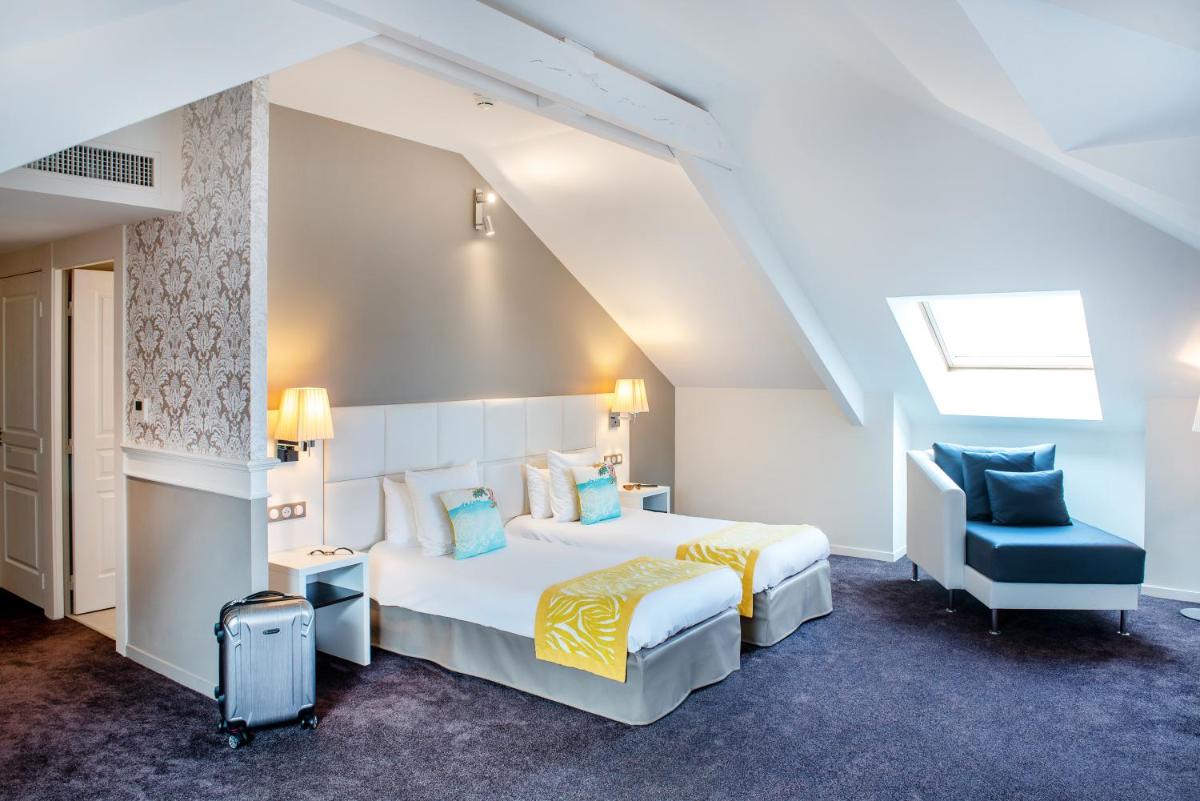 une chambre avec un lit et une chaise bleue dans l'établissement Grand Hotel Gallia & Londres, à Lourdes