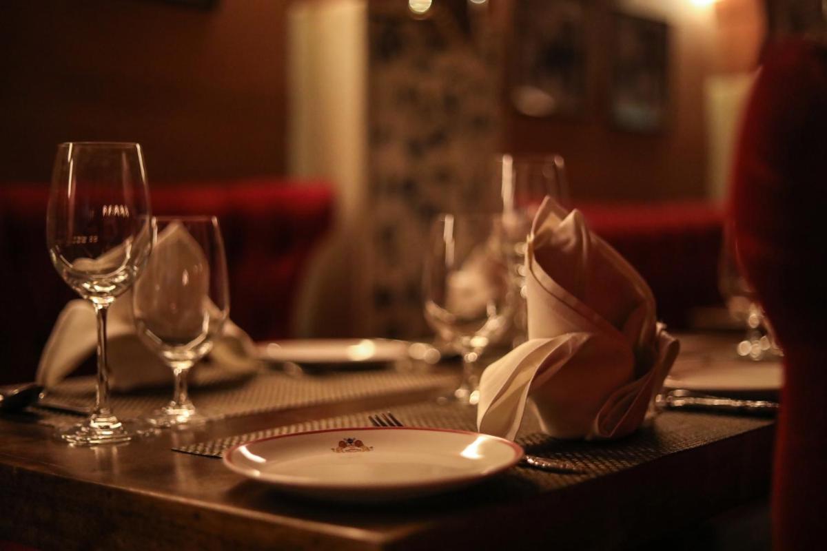 a table with a plate and wine glasses on it at Shahpura House in Jaipur