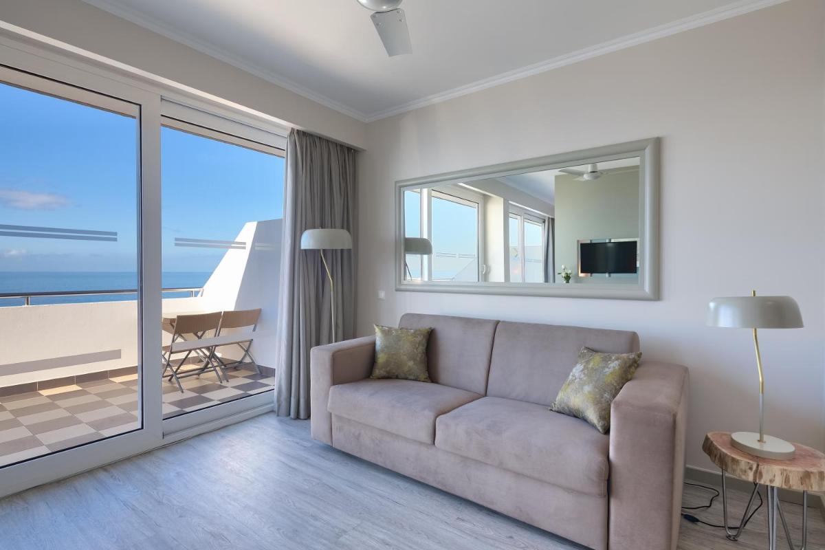 uma sala de estar com um sofá e vista para o oceano em Hotel Orca Praia no Funchal