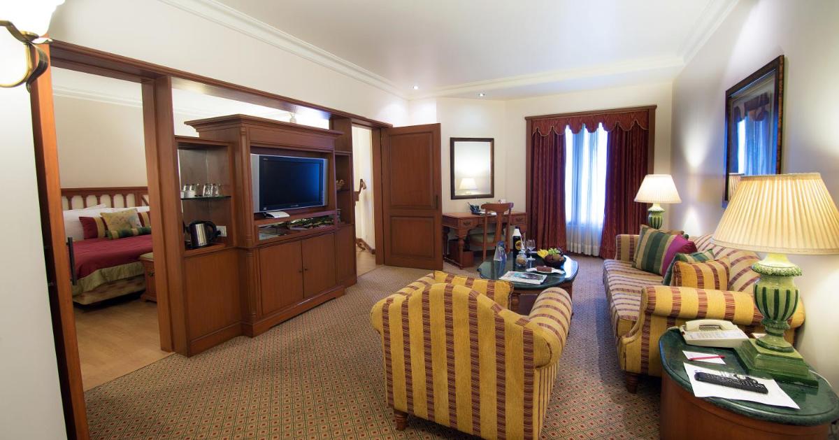 a living room with a couch and chairs and a television at The Orchid Hotel Mumbai Vile Parle in Mumbai