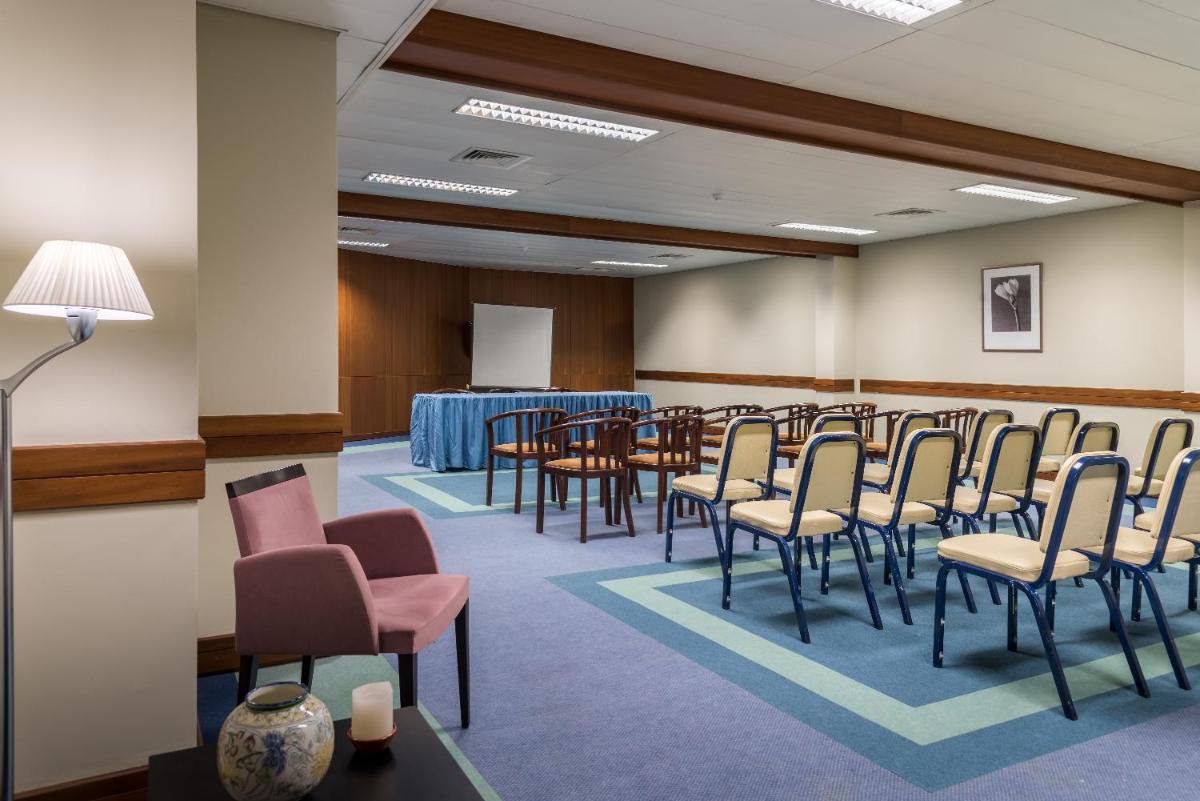 uma sala de conferências com cadeiras, uma mesa e um pódio em Enotel Magnólia no Funchal mais 66 fotografias