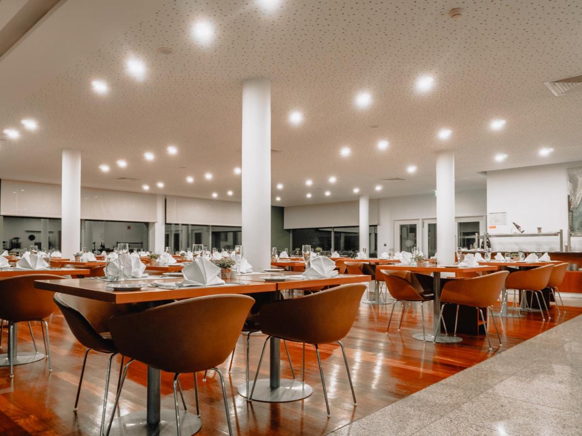 uma sala de jantar ampla com mesas e cadeiras em Monte Prado Hotel & Spa em Melgaço