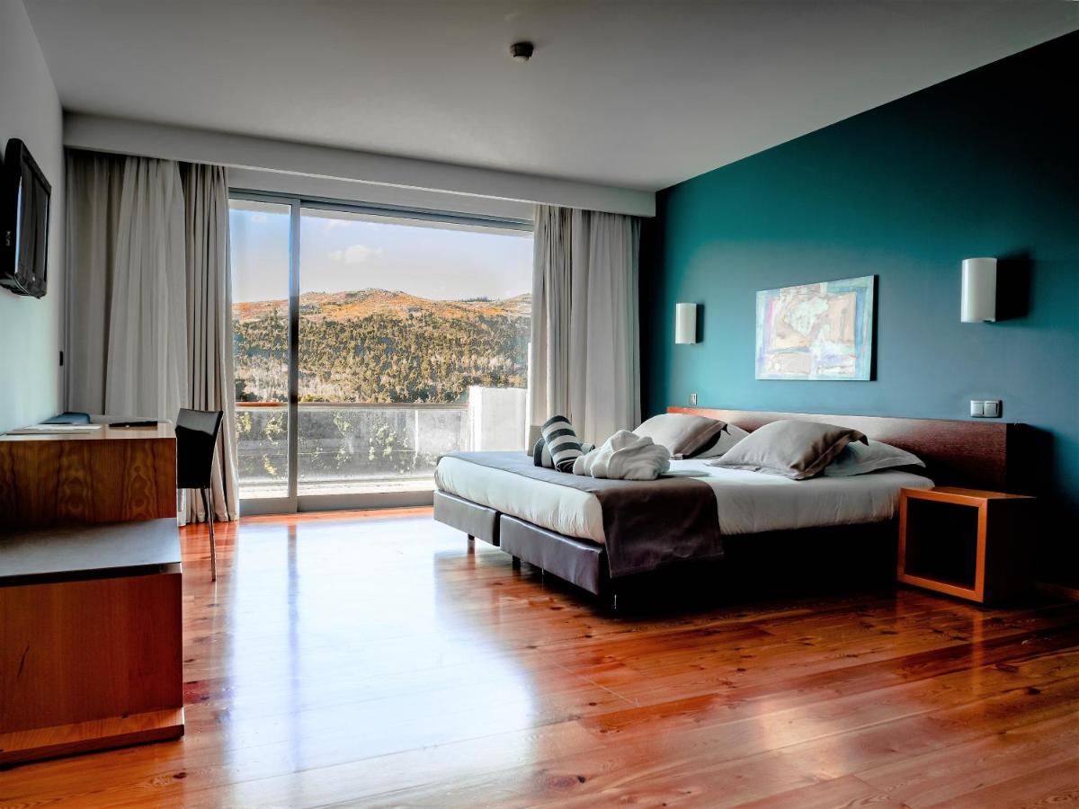 Um quarto com uma cama grande e uma janela ampla. em Monte Prado Hotel & Spa em Melgaço