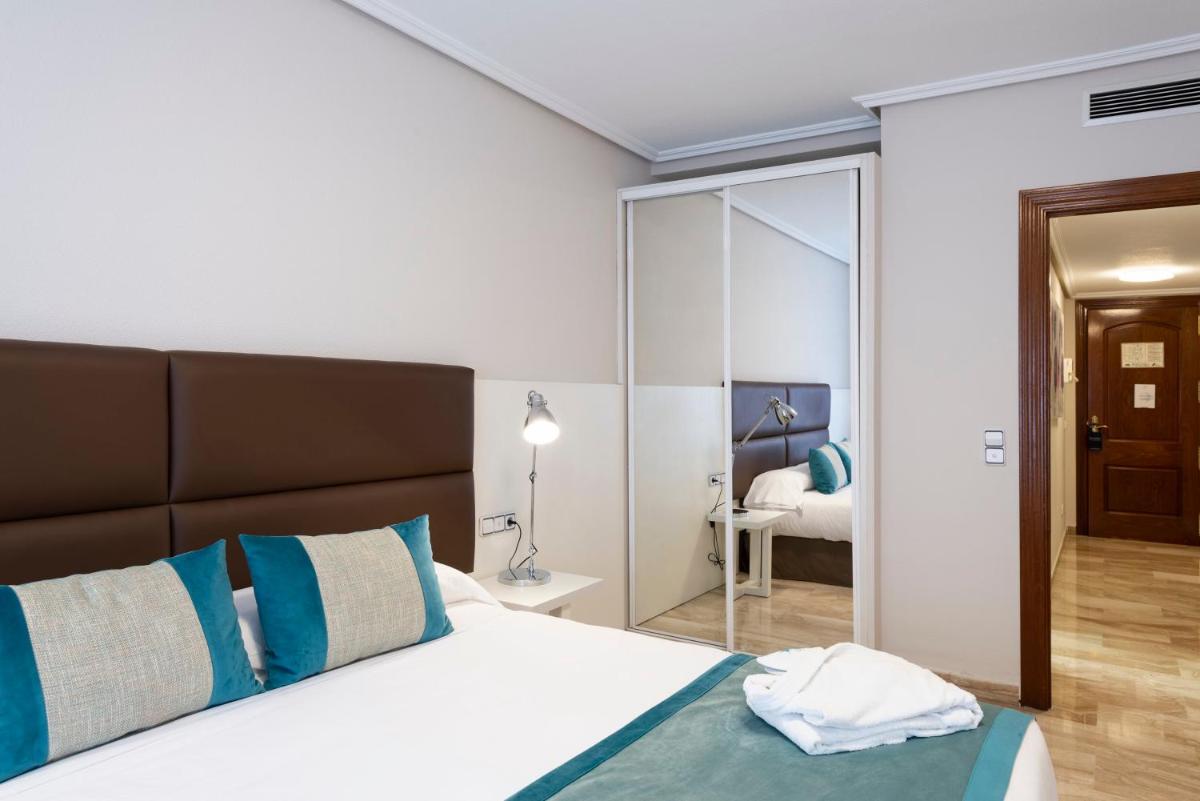 1 dormitorio con cama con almohadas azules y espejo en Aparthotel Los Girasoles, en Zaragoza 75 fotos más