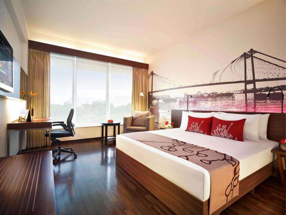 a hotel room with a large bed and a desk at Vivanta Kolkata EM Bypass in Kolkata