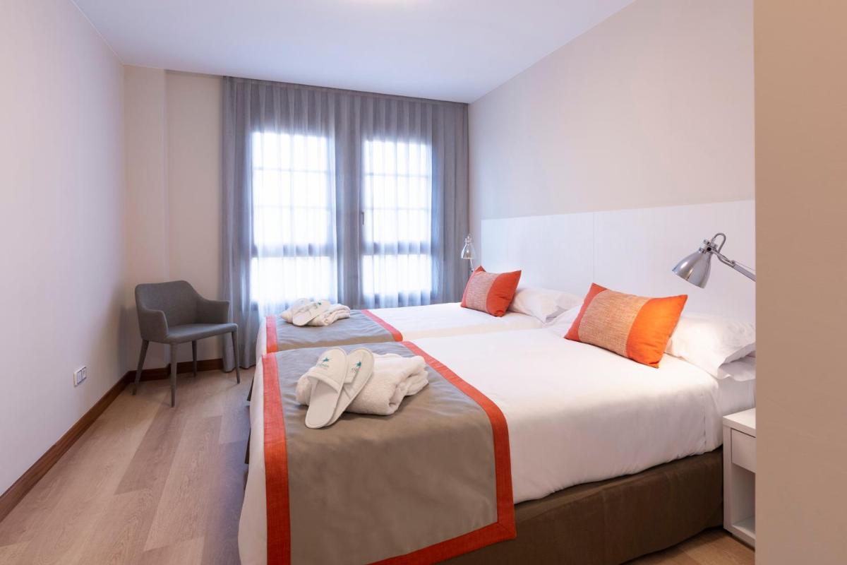 Una habitación de hotel con dos camas con toallas. en Aparthotel Los Girasoles, en Zaragoza