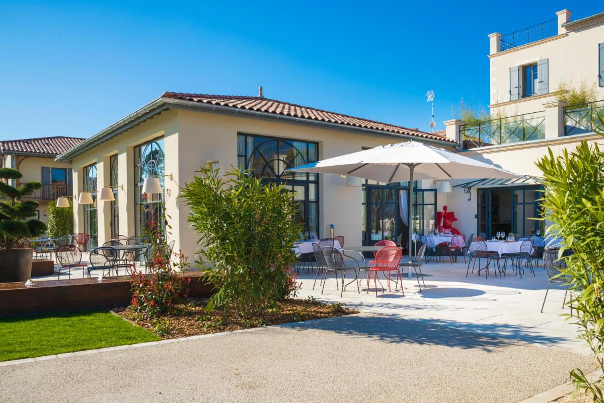 un patio avec tables, chaises et un parasol dans l'établissement Hotel Clos Castel Villas Spa, à Casteljaloux