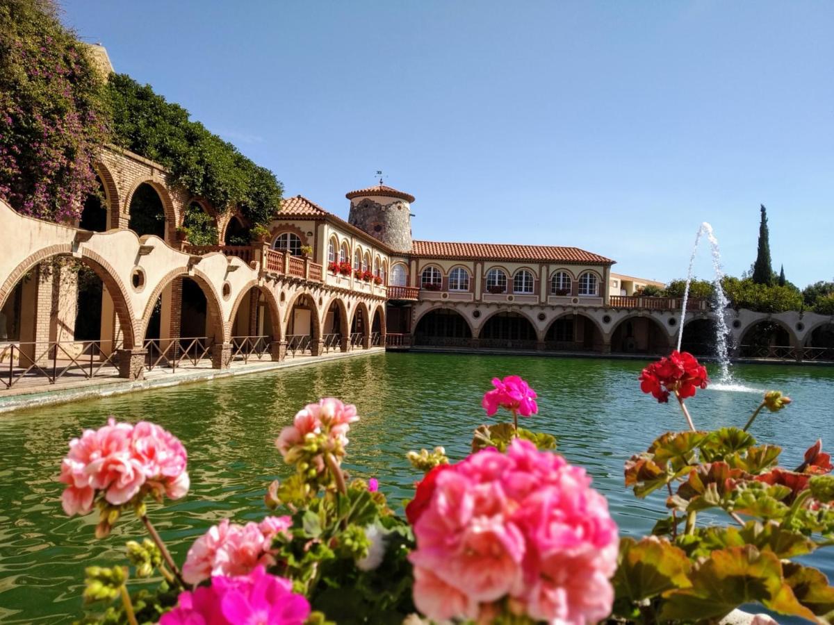 vistas a un estanque con flores rosas frente a un edificio en Termes Montbrio Hotel & Spa, en Montbrió del Camp