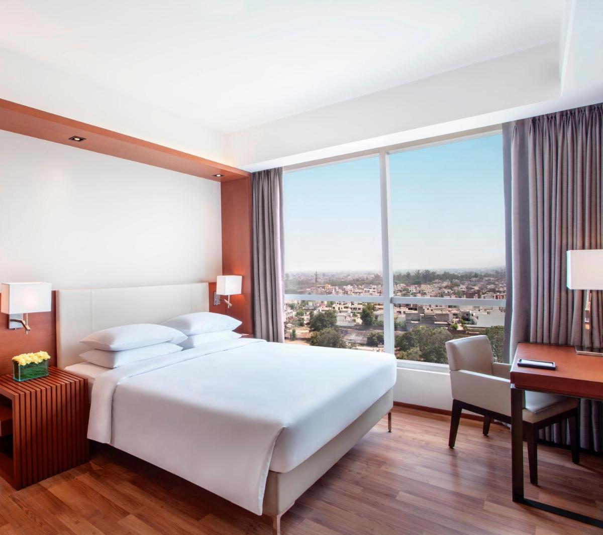 a bedroom with a large white bed and a desk at Hyatt Regency Amritsar Hotel & Spa in Amritsar