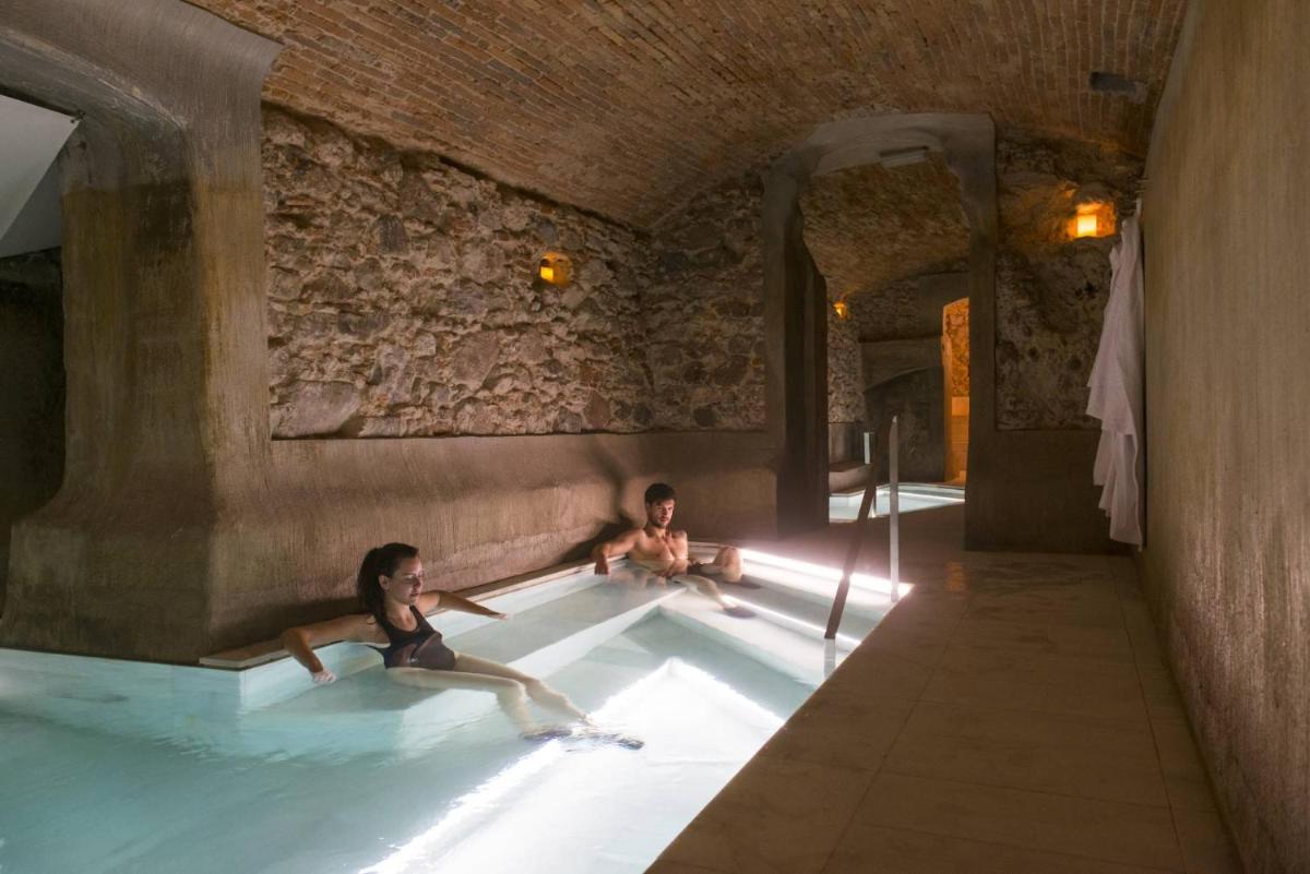 Dos personas sentadas en una piscina climatizada en Balneari Termes Victòria, en Caldes de Montbui