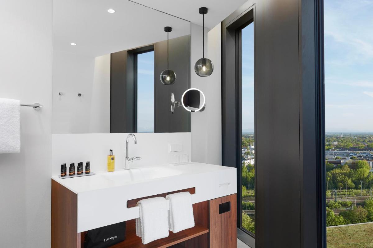 ein Badezimmer mit Waschbecken und Spiegel in der Unterkunft HYPERION Hotel München in München ein Badezimmer mit Waschbecken und Spiegel in der Unterkunft HYPERION Hotel München in München