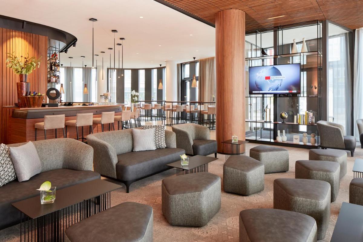 eine Lobby mit Sofas und einem TV in einem Gebäude in der Unterkunft HYPERION Hotel München in München eine Lobby mit Sofas und einem TV in einem Gebäude in der Unterkunft HYPERION Hotel München in München