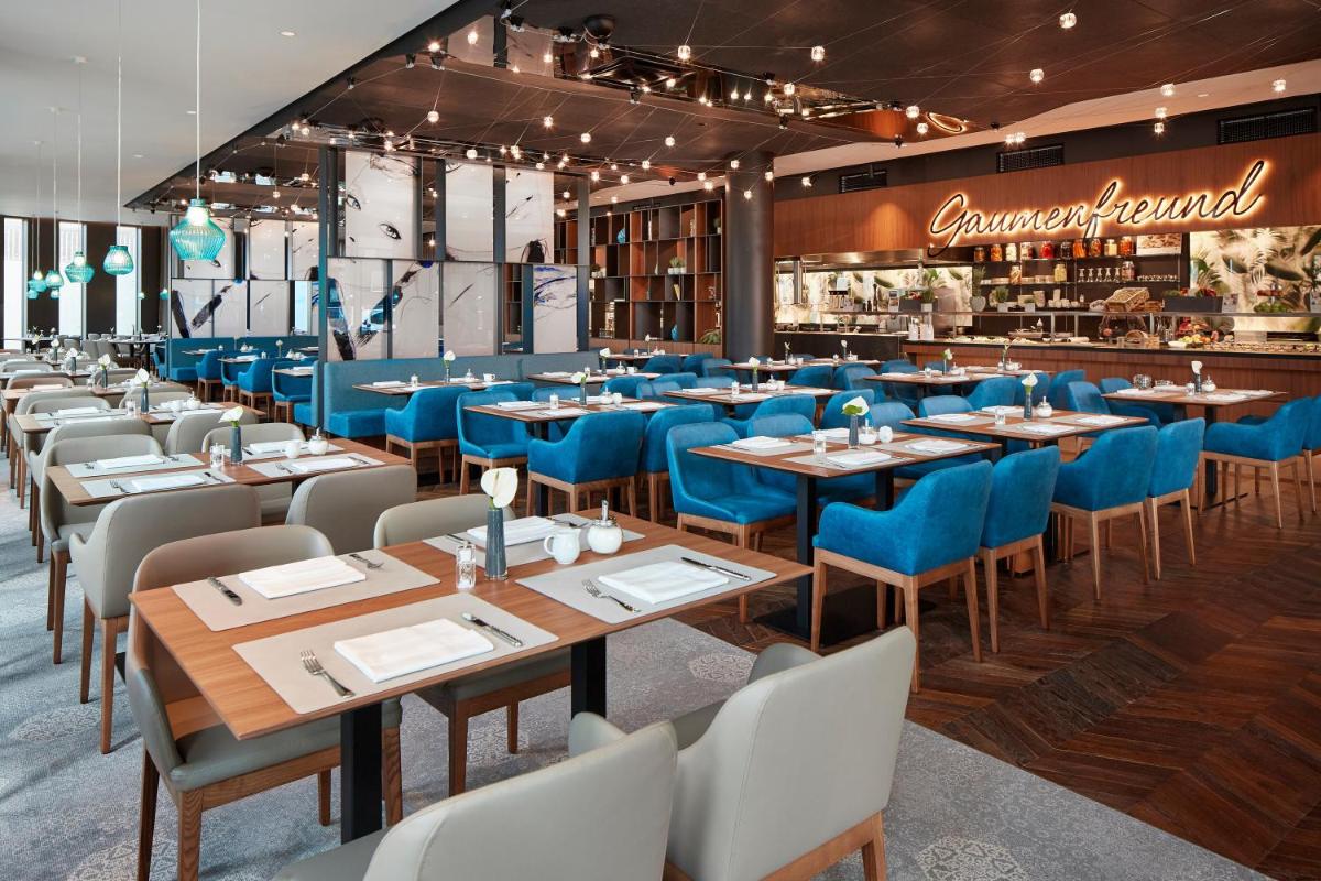ein Esszimmer mit blauen Tischen und Stühlen in der Unterkunft HYPERION Hotel München in München ein Esszimmer mit blauen Tischen und Stühlen in der Unterkunft HYPERION Hotel München in München
