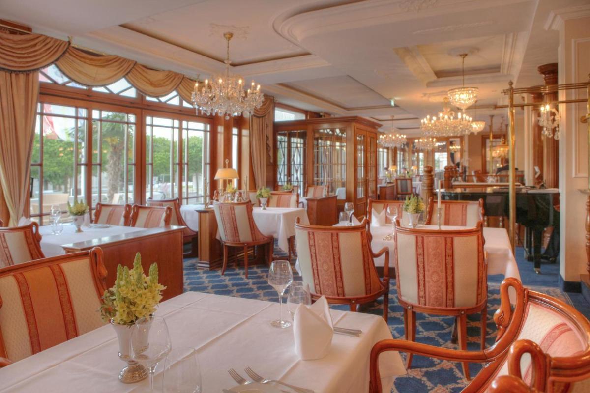 ein Restaurant mit Tischen, Stühlen und Kronleuchtern in der Unterkunft SEETELHOTEL Ahlbecker Hof das elegante Traditionshotel & ruhiger Rückzugsort an der Ostsee in Ahlbeck