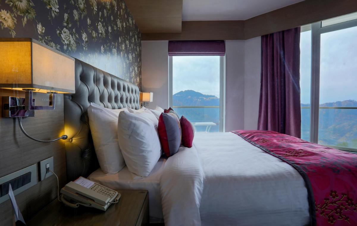 a hotel room with a bed with a phone next to a window at Welcomhotel by ITC Hotels, Shimla in Shimla