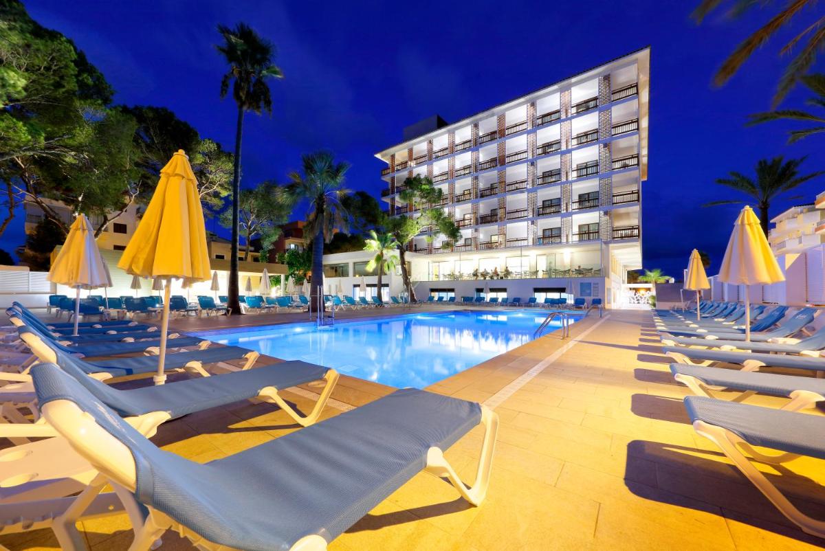 Una piscina con tumbonas y un hotel. en Talayot - Adults Only, en Cala Millor